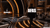 a man walking on a stage with the word afas on his back