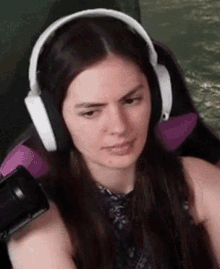a woman wearing headphones is sitting in a chair and making a face .