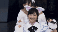 a girl wearing a cat ear headband is smiling while holding a microphone
