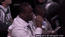 a man is sitting in the stands drinking water from a bottle .