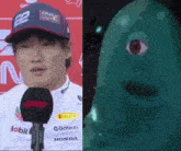 a man wearing a hat is talking into a microphone next to a green monster with a red eye .