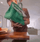 a man is holding a green bag over his face