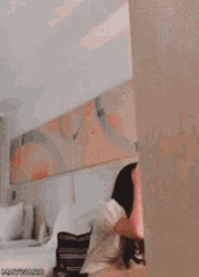 a woman is laughing with her hands in the air while standing in front of a wall .