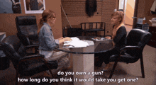 two women are sitting at a table talking about guns