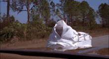 a man in a white robe is driving down a road