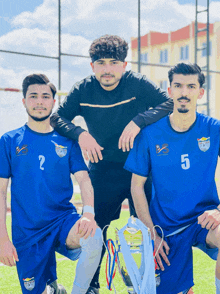 two soccer players wearing blue jerseys with the number 2 and 5 pose for a photo