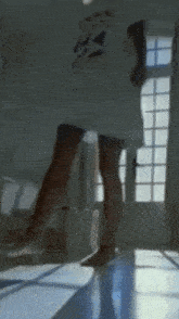 a woman 's legs are shown in a blurry photo with a window in the background