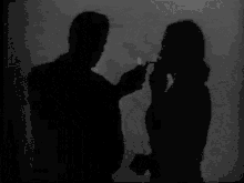 a man is lighting a woman 's cigarette with a lighter in a black and white photo .