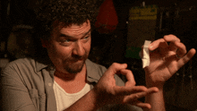 a man in a gray shirt is holding a piece of paper in his hands