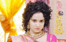 a woman with curly hair is wearing a pink and gold necklace