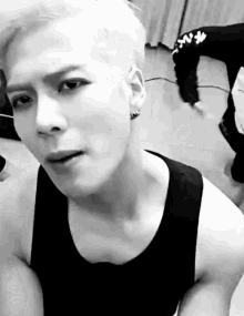 a black and white photo of a young man wearing a tank top