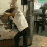 a man is playing an acoustic guitar and singing into a microphone while standing on a stool .