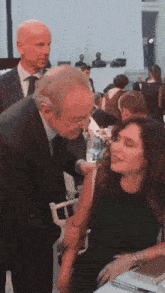 a man in a suit kisses a woman on the cheek