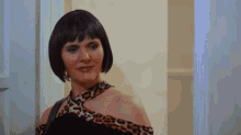 a woman in a black and leopard print dress stands in a doorway
