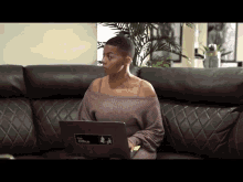 a woman sitting on a couch with a laptop that says the office on it