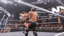 two wrestlers in a ring with a n on the wall