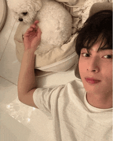 a man is laying on a bed with a small white dog