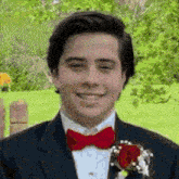 a man in a suit and red bow tie is smiling for the camera
