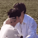 two men are kissing in a field and one of them is hugging the other .