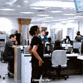 a woman in a black shirt stands in an office and says i love my life