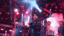 a man holding a trophy in front of a crowd with confetti falling around him