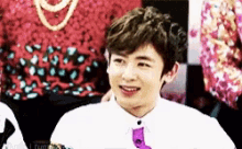 a young man wearing a white shirt and purple tie is smiling