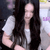 a woman with long black hair is sitting in front of a sign that says ' a ' on it