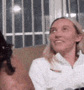 a woman in a white shirt is sitting on a couch with a cat in her lap .