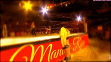 a woman in a wrestling ring stands in front of a sign that says miami raw
