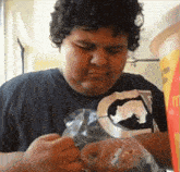 a man in a black shirt with the letter g on it is holding a bag of food