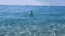 a person swimming in the ocean with a boat in the background