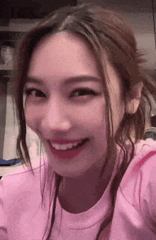 a close up of a woman 's face with a pink shirt on