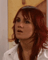 a close up of a woman 's face with red hair and a white shirt