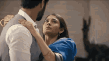 a man and a woman are standing next to each other and the woman is holding the man 's shoulder .