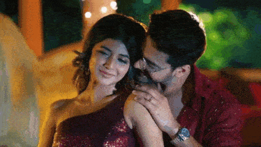 a man is kissing a woman on the cheek while she smiles .
