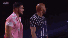 two men are standing next to each other in front of a sign that says all elite wrestling