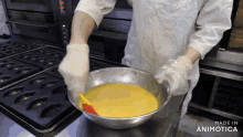 a person is mixing a yellow liquid in a metal bowl with a spatula and the words made in animotica behind them
