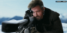 a man holding a rifle with a pranay varma logo above him