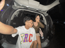 a man wearing a shirt that says src stands next to a woman covering her mouth