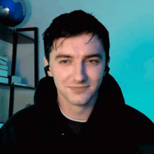 a man wearing headphones looks at the camera with a blue background