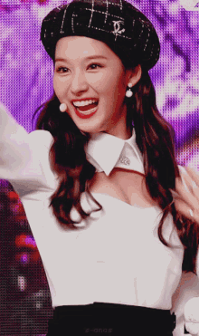 a close up of a woman wearing a beret and a white shirt with the word s-angs on the bottom