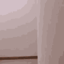 a woman is peeking out from behind a white wall .