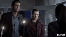 a man in a suit and a woman in a purple coat are standing next to each other in front of a netflix logo