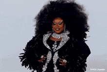 a woman with a very large afro wearing a black and silver outfit