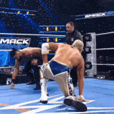 two men are wrestling in a wrestling ring with the word mack down on the wall