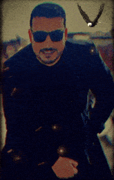 a man wearing sunglasses and a black jacket stands in front of a bird