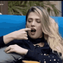 a woman is sitting on a blue couch eating a piece of food .