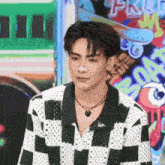 a young man with a nose ring is wearing a plaid shirt and a heart necklace