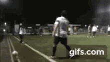 a man is kicking a soccer ball on a field at night