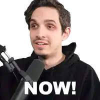 a man in front of a microphone with the word now on his face